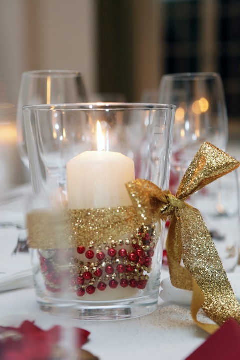 Schlicht und dennoch elegant wirkt dieses Windlicht mit rot-goldenen Perlen und passender Schleife. (Bild: Bilderstoeckchen - Fotolia)